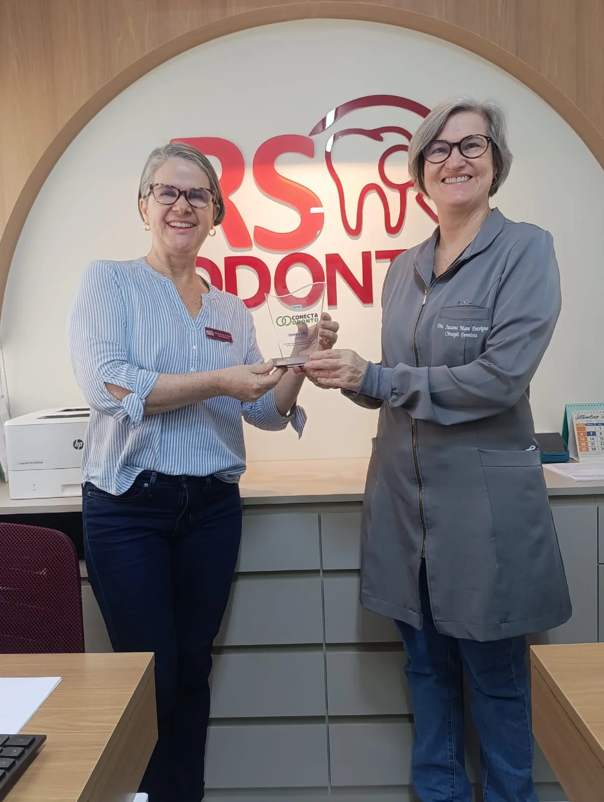 Dra. Suzana Mara Entrigue recebendo o troféu Conecta Odonto na recepção da RS ODONTO